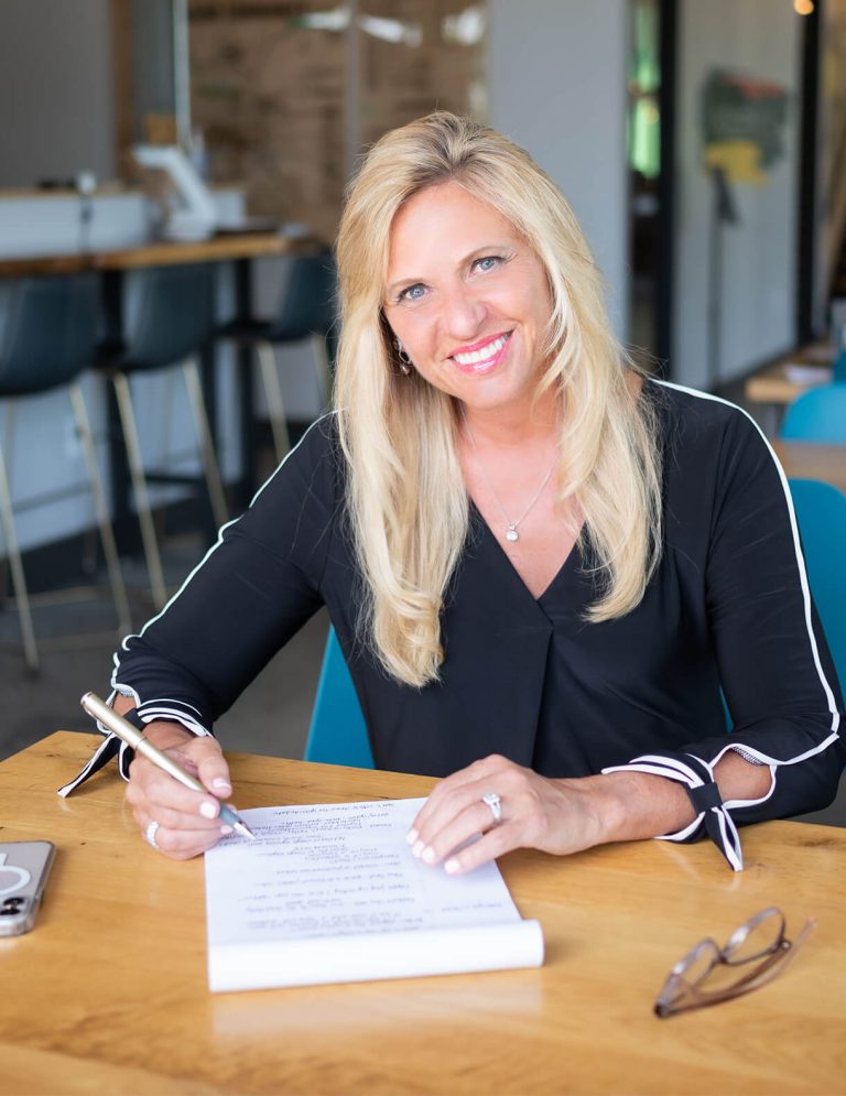 Image of CEO, Deb Rishel, writing on a notepad at Paradigm Digital Group offices